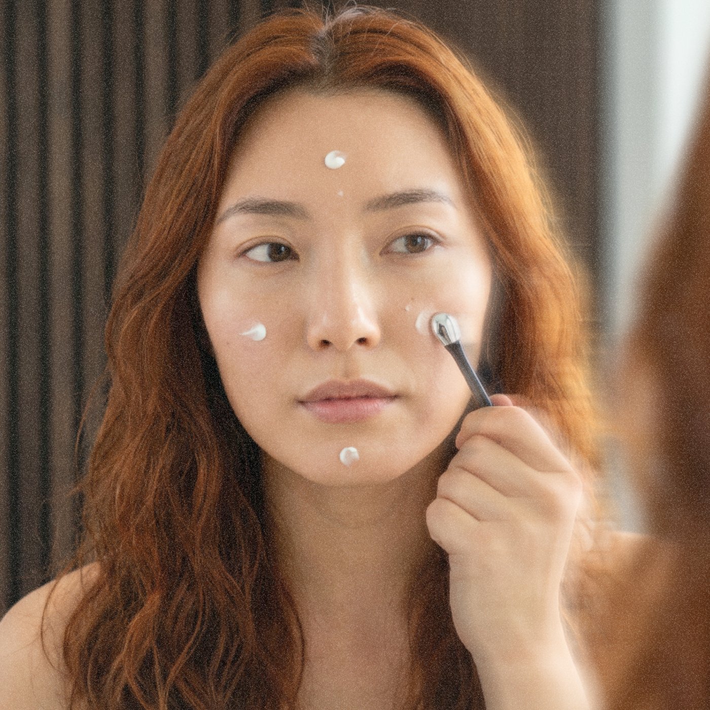 Pressing Crème Régénérante onto the cheeks and forehead with the spatula.