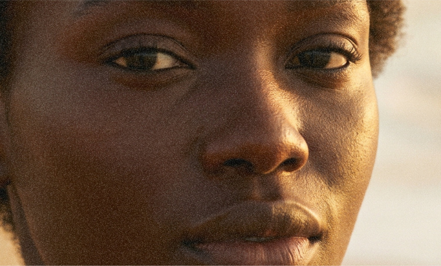 A face holds the camera, golden side light, focus on the cheek and brow.